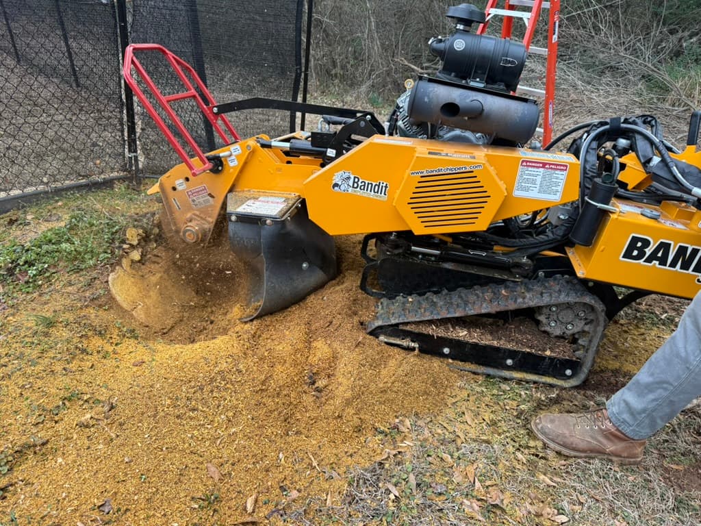 Bandit SG-40 stump grinder grinding near a fence line with wood chips flying